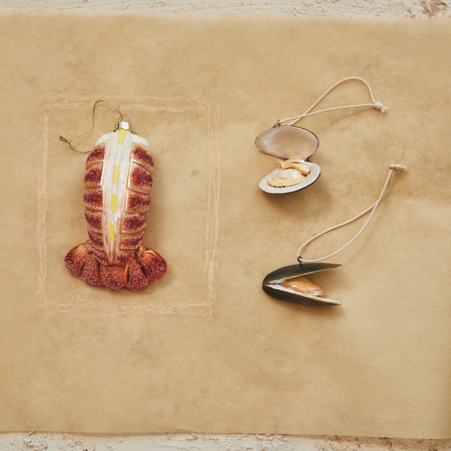 lobster tail glass ornament alongside a clam and mussel ornament 