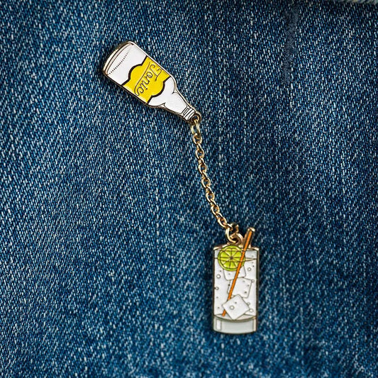 gin and tonic enamel pin -- tonic bottle is connected to glass filled with ice, gin & tonic, lime and a straw and is placed above the glass to look like it's pouring into the glass