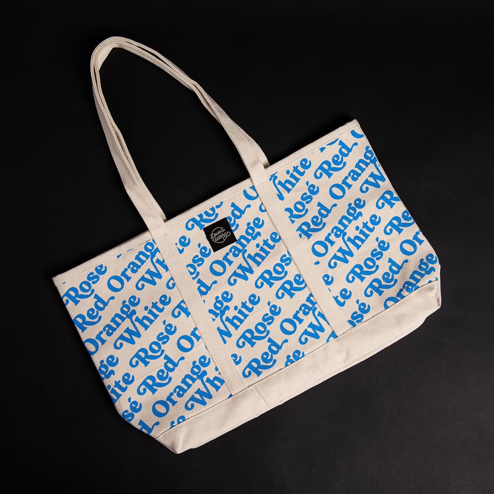 Wine Bottle tote bag with blue print. Repeat pattern that says White, red, rosé and orange.