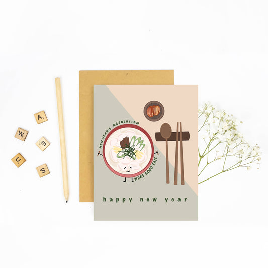 greeting card for lunar new year -- has illustration of dduk gook (rice cake soup), kimchi and a set of chopsticks and a spoon. Text reads "The new year's resolution: more good eats. Happy new year."