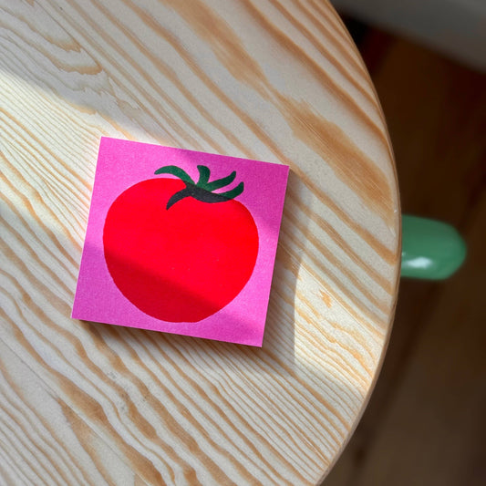 Pink post-it note pad with a red tomato illustration on it