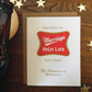 Miller High Life beer themed card with 'Marriage High Life' and 'The Champagne of Celebrations' design on a wooden surface with decorative stars.