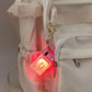 Mini microwave keychain lit up and attached to a beige backpack