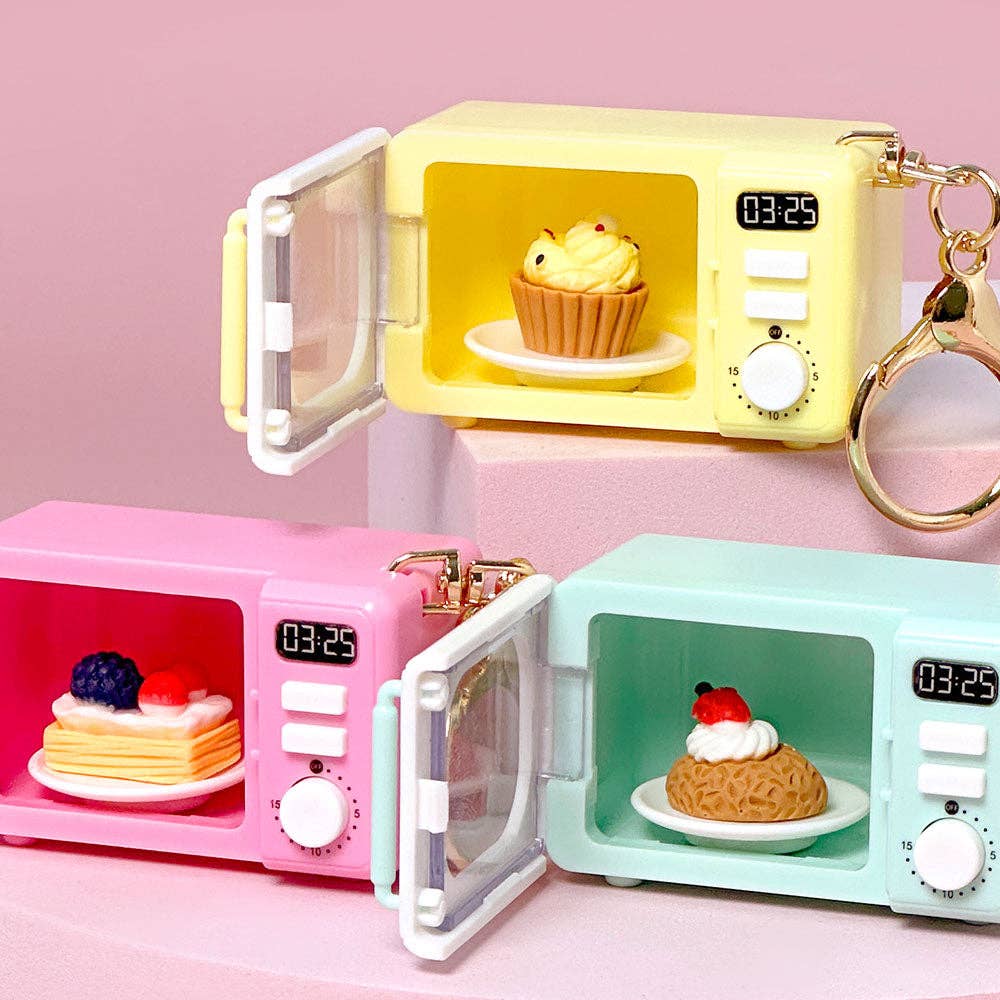 Three colorful mini microwaves with food inside on a pink background