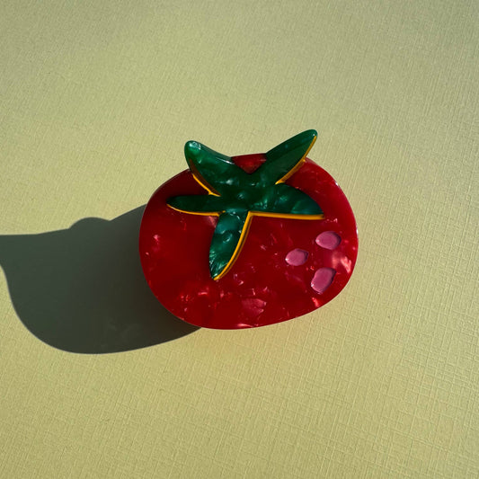 Tomato-shaped mini hair claw with green leaves on a beige background