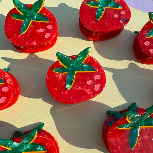 Red tomato-shaped mini hair claws with green leaves on a beige background