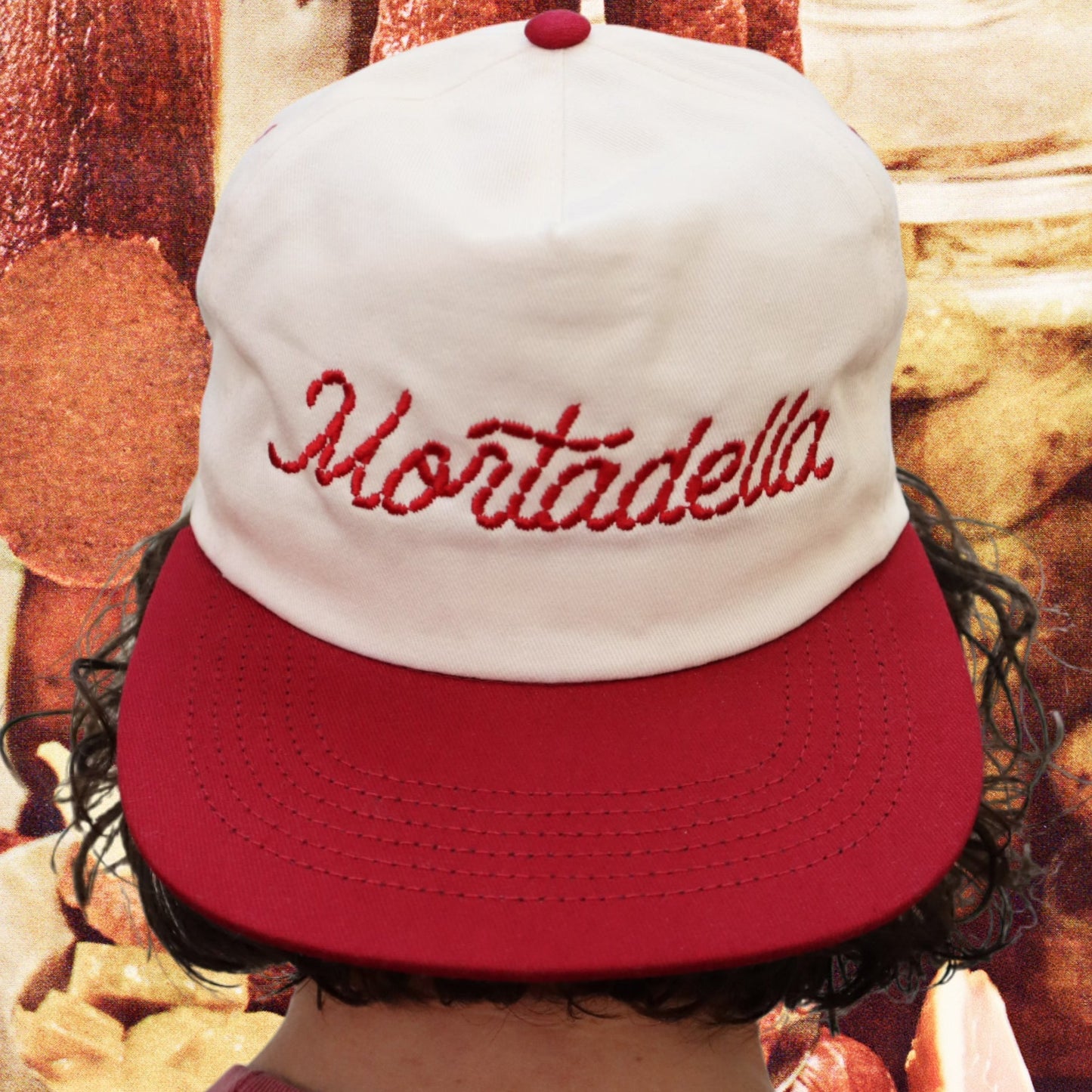 red and white hat with red stitching that says "mortadella" 