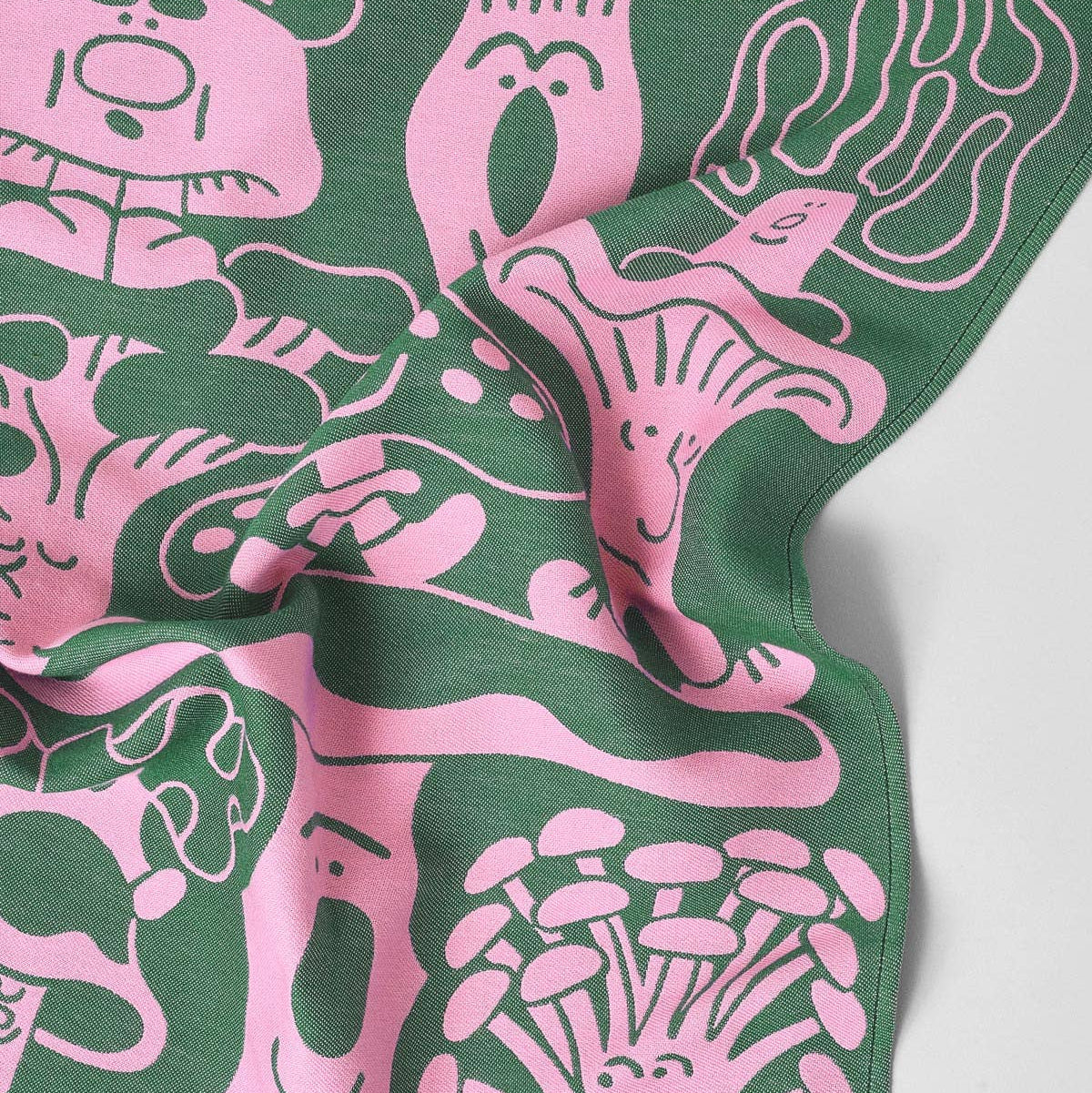 Green fabric with pink abstract mushroom patterns on a towel with a white background