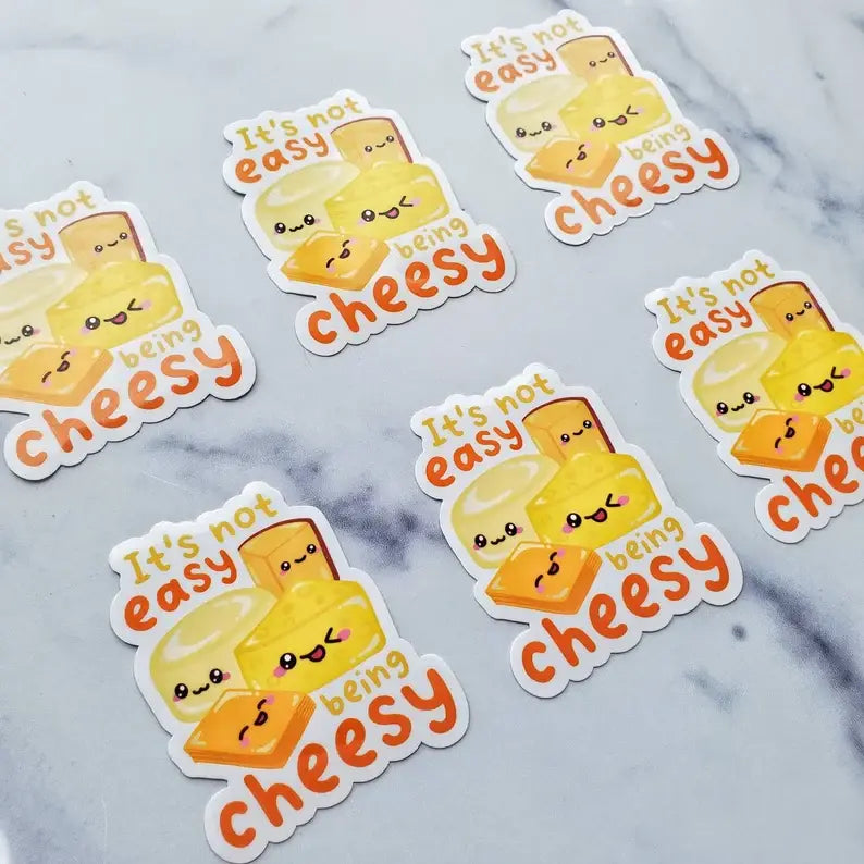 Stickers with a cheese design and text 'It's not easy being cheesy' on a marble background.
