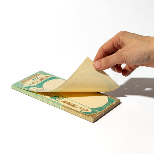 Hand holding page from the oat milk carton notepad pictured on a white background 