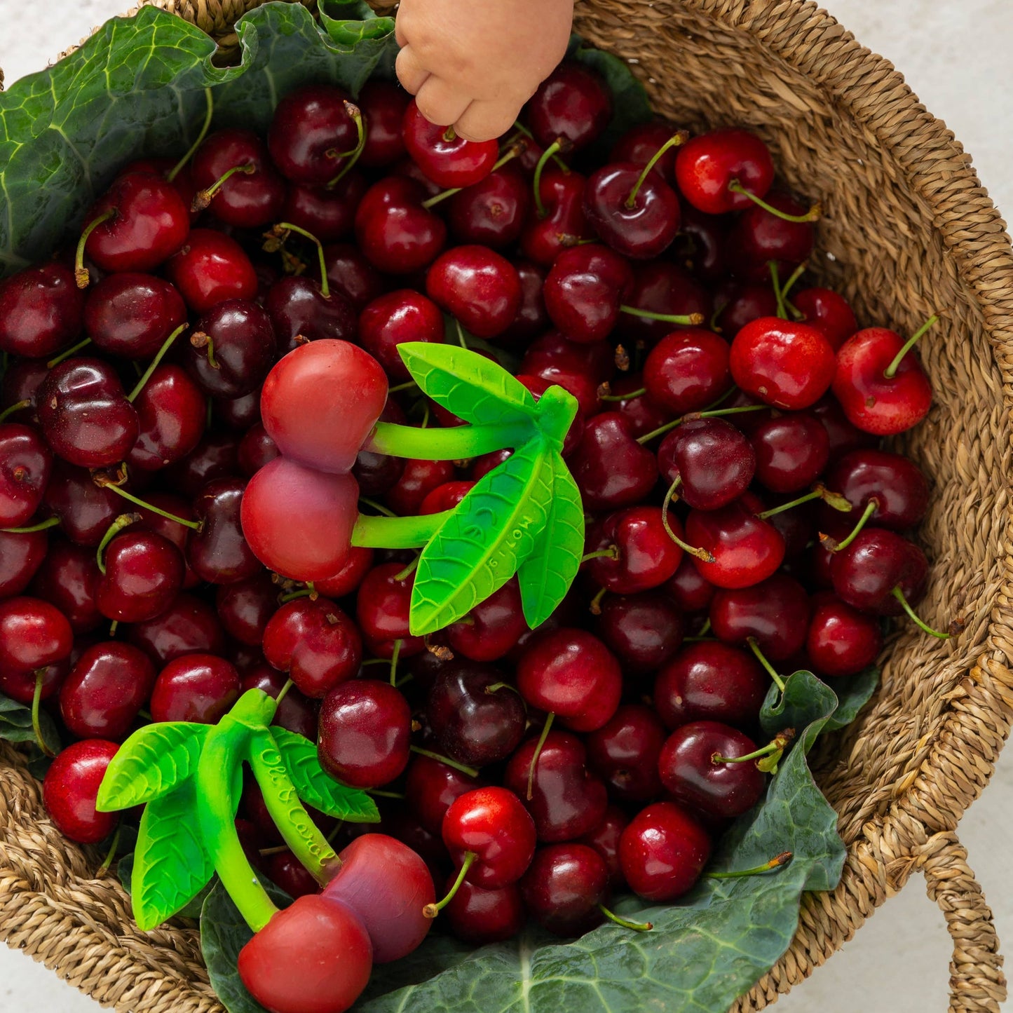 image of cherry teething toys in a basket of real cherries 