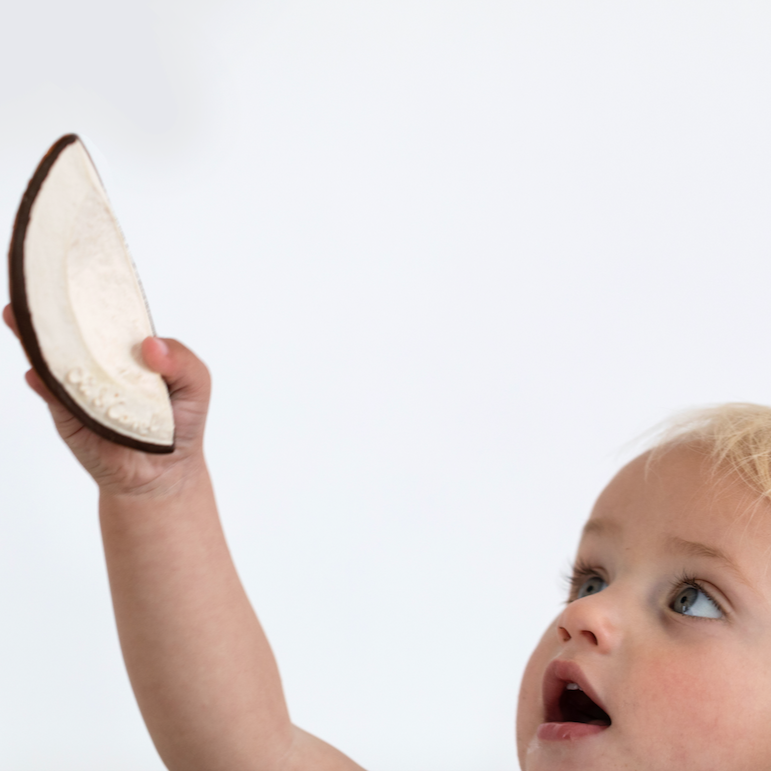 coconut baby teether/toy being held by a baby 