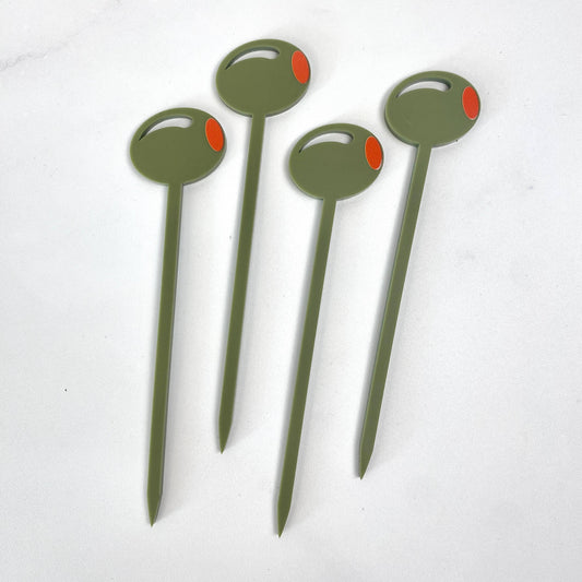Four cocktail picks with a green olive design on th end, on a white background