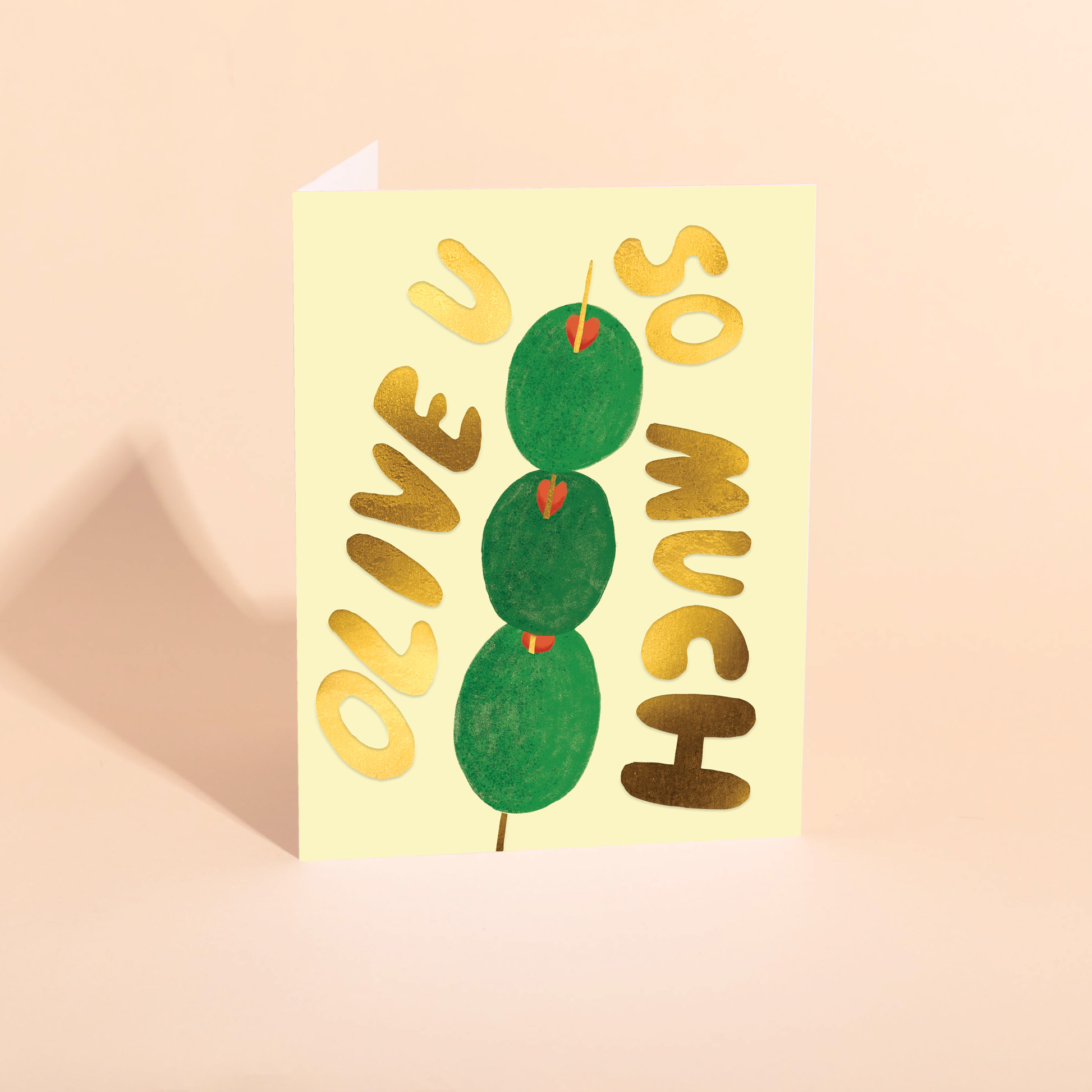 Greeting card with stuffed green olives on a pick and gold text "olive u so much" on a beige background