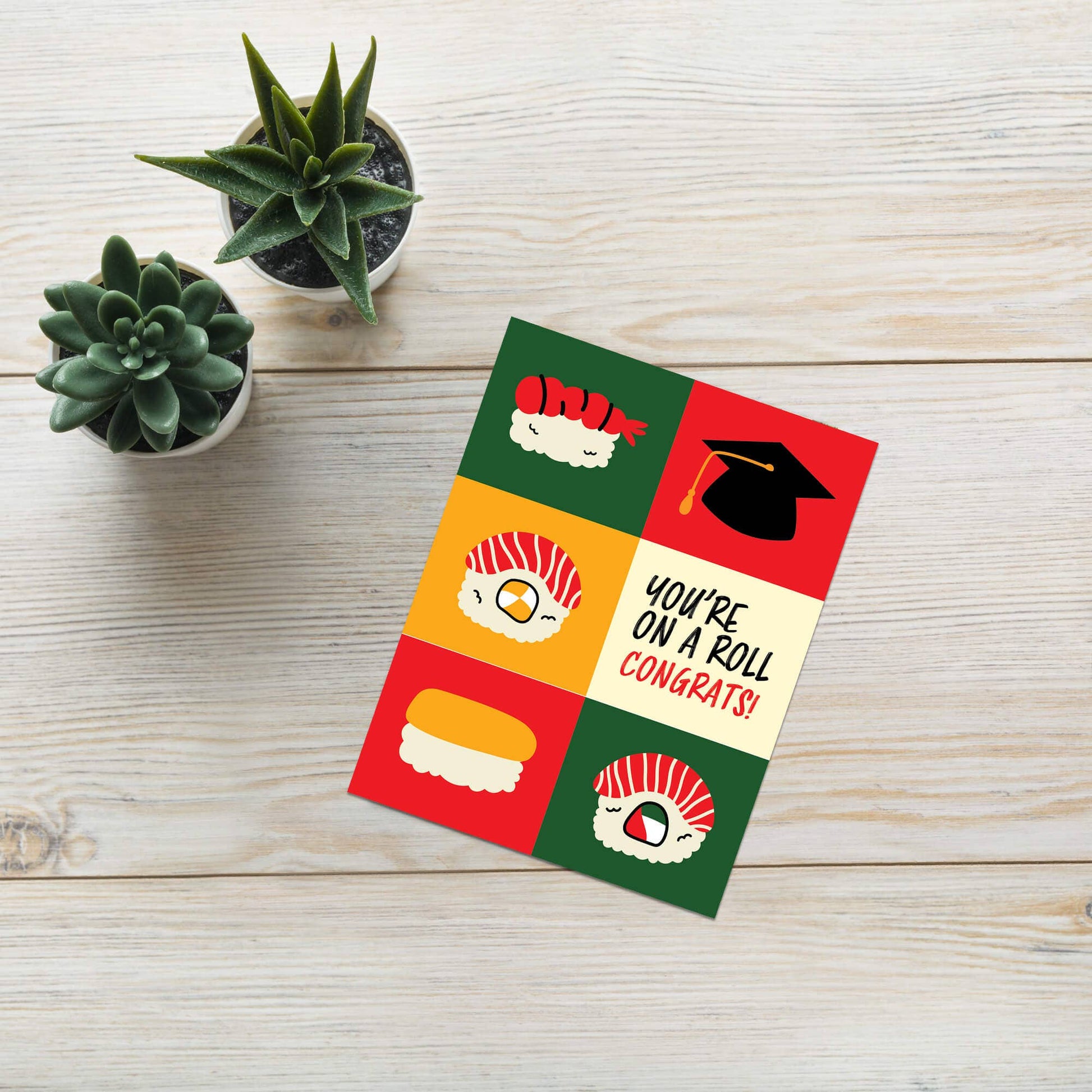 Colorful card with sushi illustrations and text on a wooden surface with plants