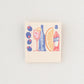 Spritz matchbook shown closed, with image on cover of Campari, orange wedge, bubbles, spritz in a glass and olives on a pick.