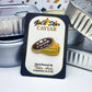 Gold Star Caviar packaging for the caviar enamel pin with orange fish eggs, with tinned fish containers in the background