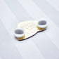 Back of the caviar tin enamel pin with  'TOKU ARTS' branding and two white, rubber backings on a light gray background