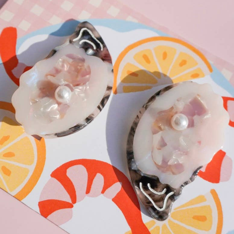 Oyster shell shaped clips with pearls on a colorful background