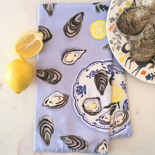 patterned towels with oyster and lemon design on a marble surface with lemons and oysters.