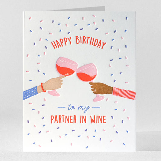 Birthday card with illustration of two hands holding wine glasses and text 'Happy Birthday to my partner in wine' on a white background.