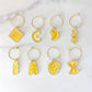 Set of 8 yellow pasta-shaped drink charms with gold ring on a marble background