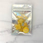 Packaged gold, pasta wine charms with a clear front bag on a marble surface