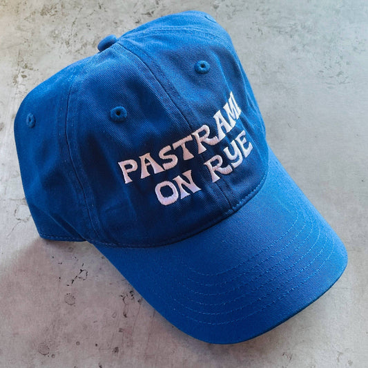 blue baseball cap with white embroidered text that reads "pastrami on rye" 