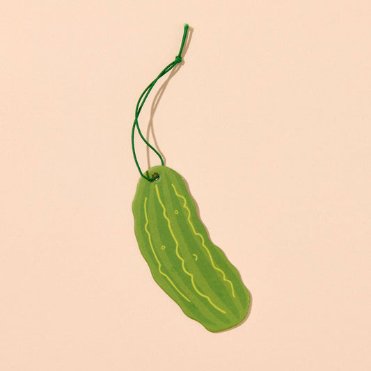 Green pickle-shaped air freshener on a beige background