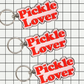Three 'Pickle Lover' keychains on a grid background