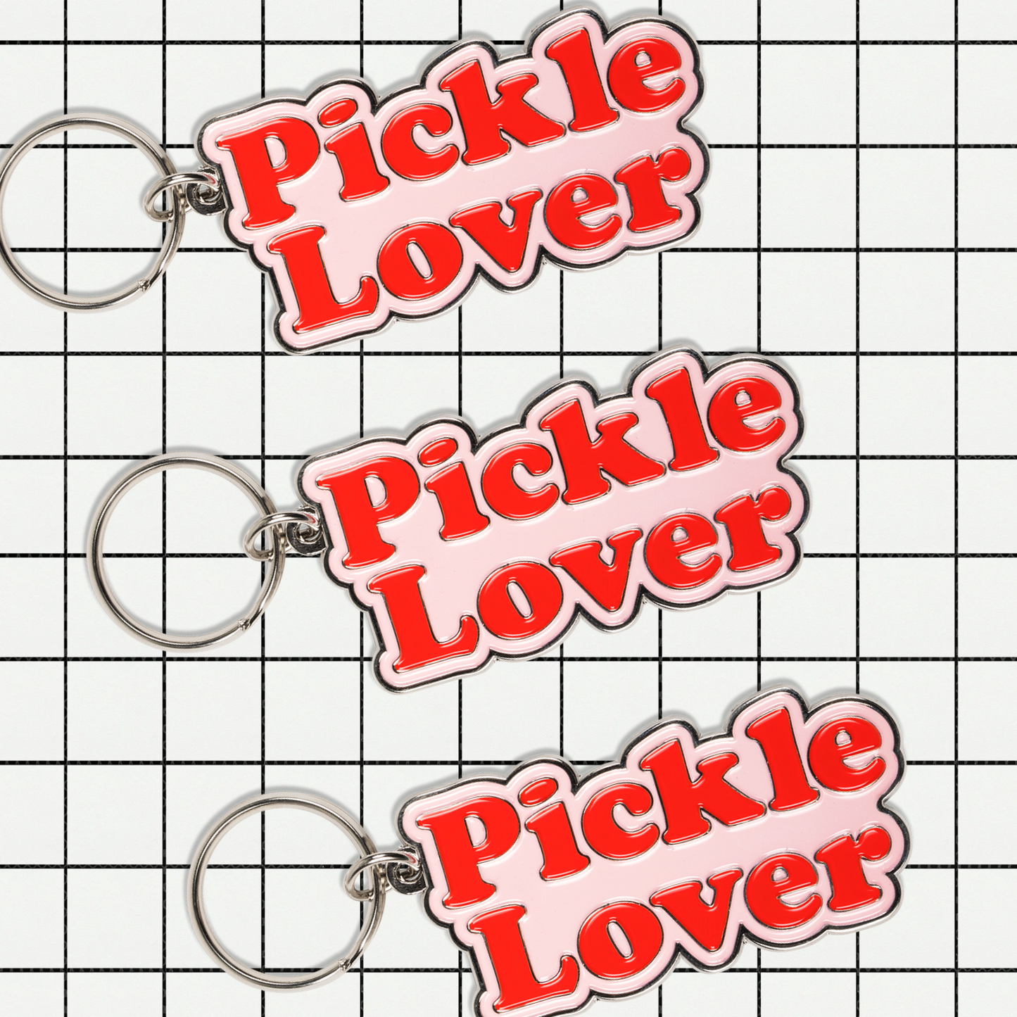 Three 'Pickle Lover' keychains on a grid background