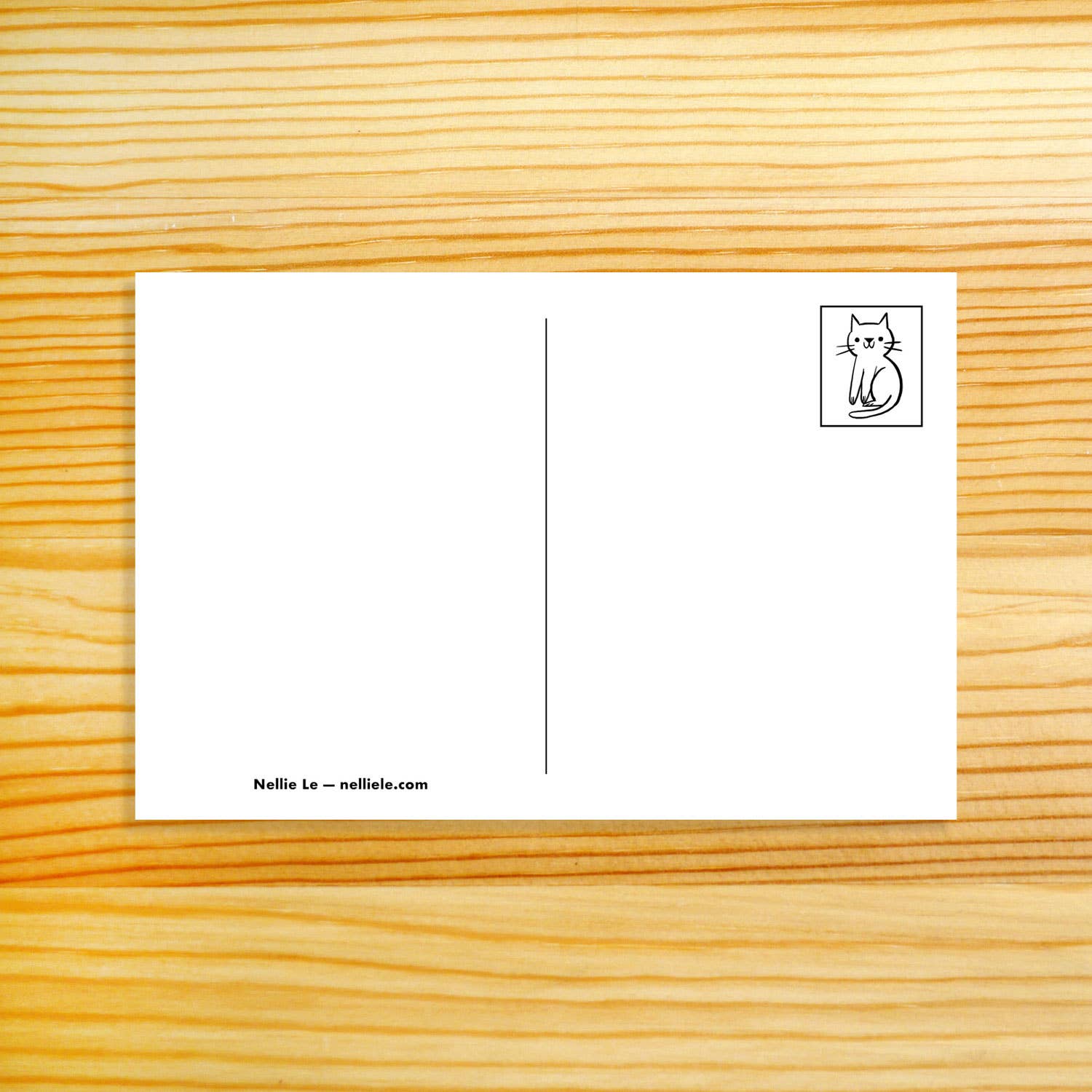 A white postcard with a vertical center line, a small black cat illustration in the top-right corner, and the text 'Nellie Le - nellilele.com' at the bottom left, placed on a light wood grain background.