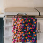 Botanical fruits tea towel in pink and teal on stove top towel bar 