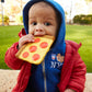 Child holding a toy pizza slice outdoors