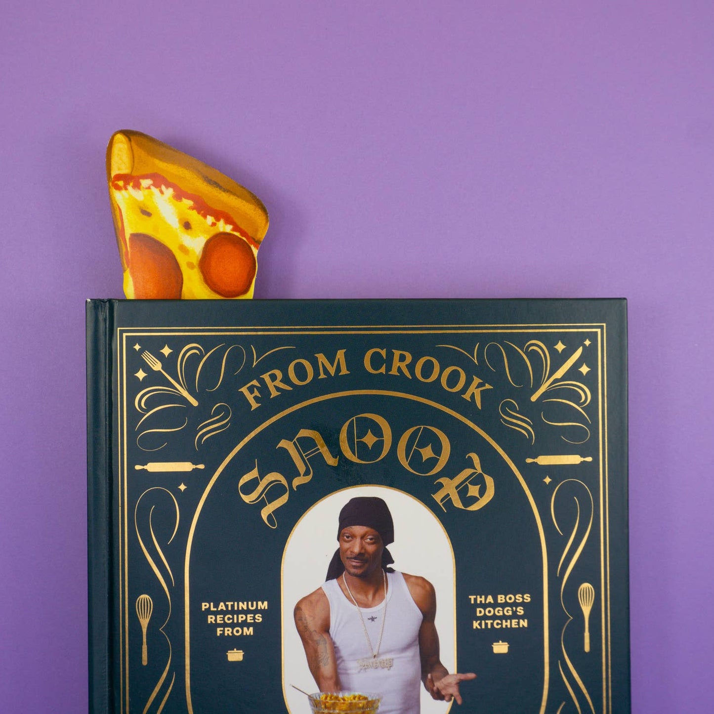 Book with a pizza slice bookmark inside on a purple background