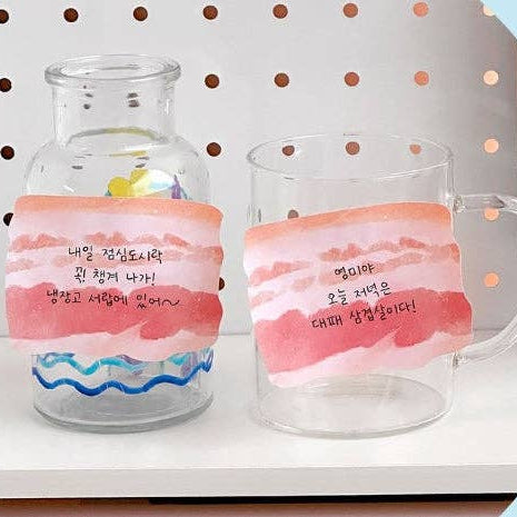 Clear glass jar and mug with memo notes that look like slices of pork belly on it 