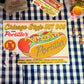 Table with food and a Portillo's hot dog sign on a checkered tablecloth