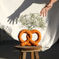 salted pretzel shaped vase being photographed on wooden stole with baby's breath flowers inside 