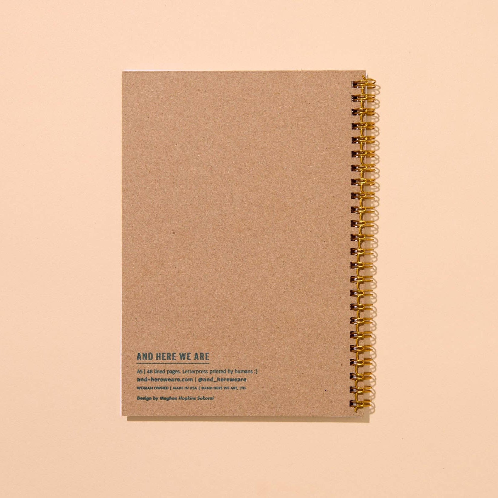 notebook brown cardboard backing with gold spiral binding on a beige background