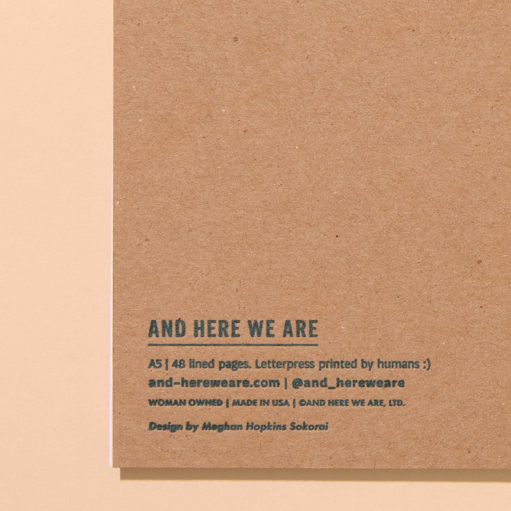 Brown cardboard backing with text about 'And Here We Are' brand on a beige background