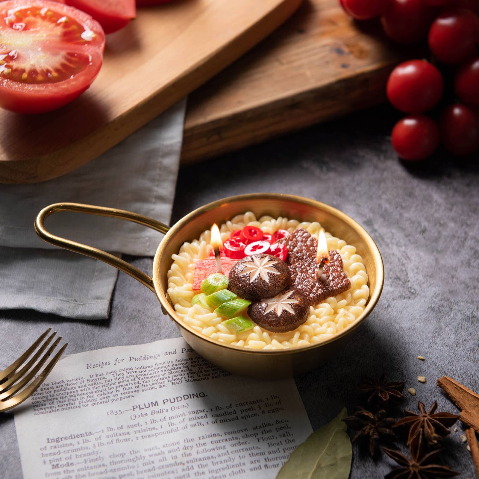 candle made to look like korean ramen noodles in gold pot with toppings such as mushrooms, beef, green onions and peppers on it