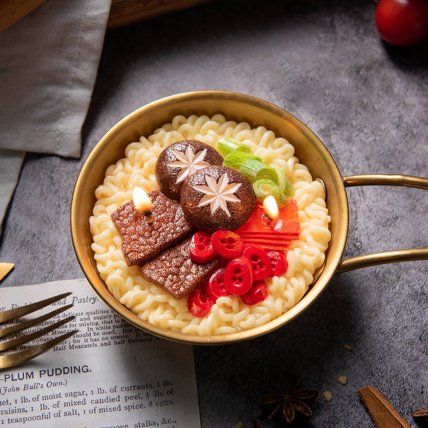 Gold ramen bowl with noodles, mushrooms, and vegetables on a dark surface
