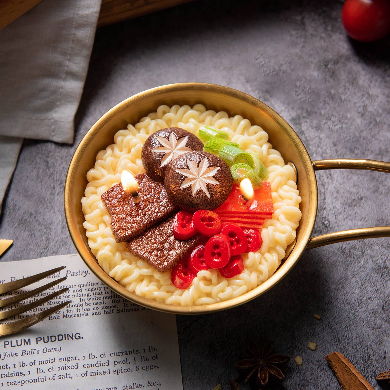 Gold ramen bowl with noodles, mushrooms, and vegetables on a dark surface