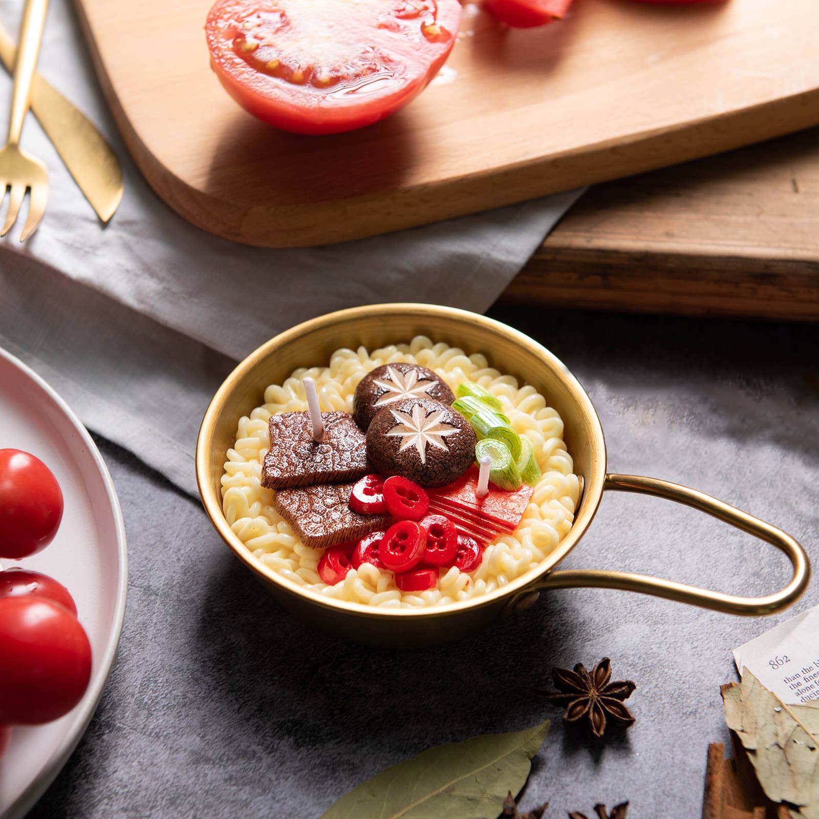 candle made to look like korean ramen noodles in gold pot with toppings such as mushrooms, beef, green onions and peppers on it