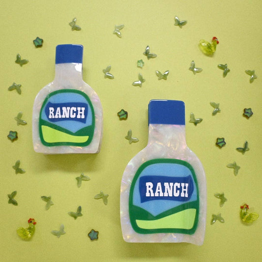 Two Ranch dressing hair claws  on a yellow background with decorative elements.