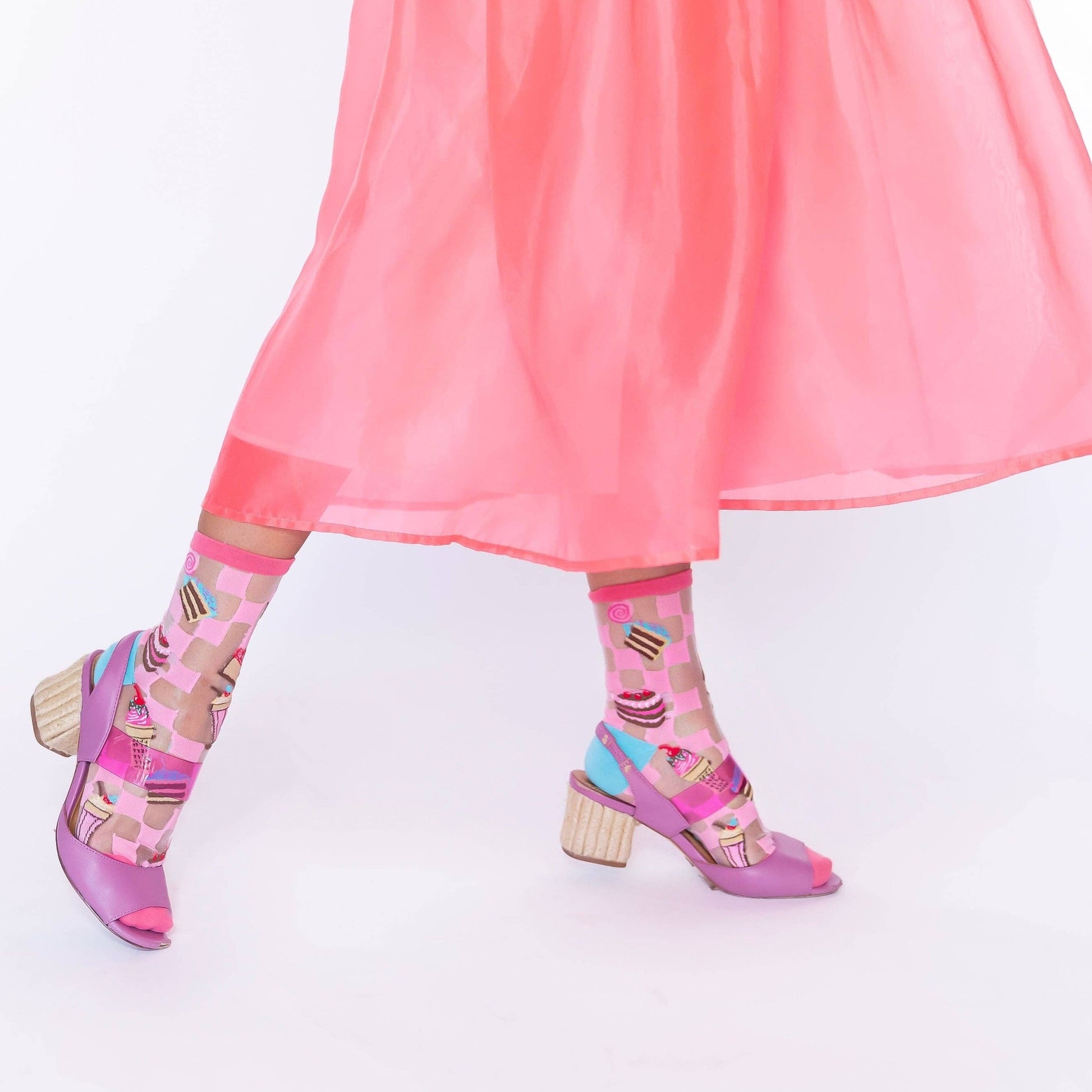 Pink, sheer, women's socks on model -- socks have cakes, ice cream, milkshakes and candy on them 