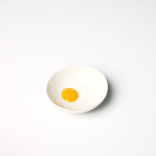 Small ceramic bowl designed to look like a sunny side up egg pictured here on a white background