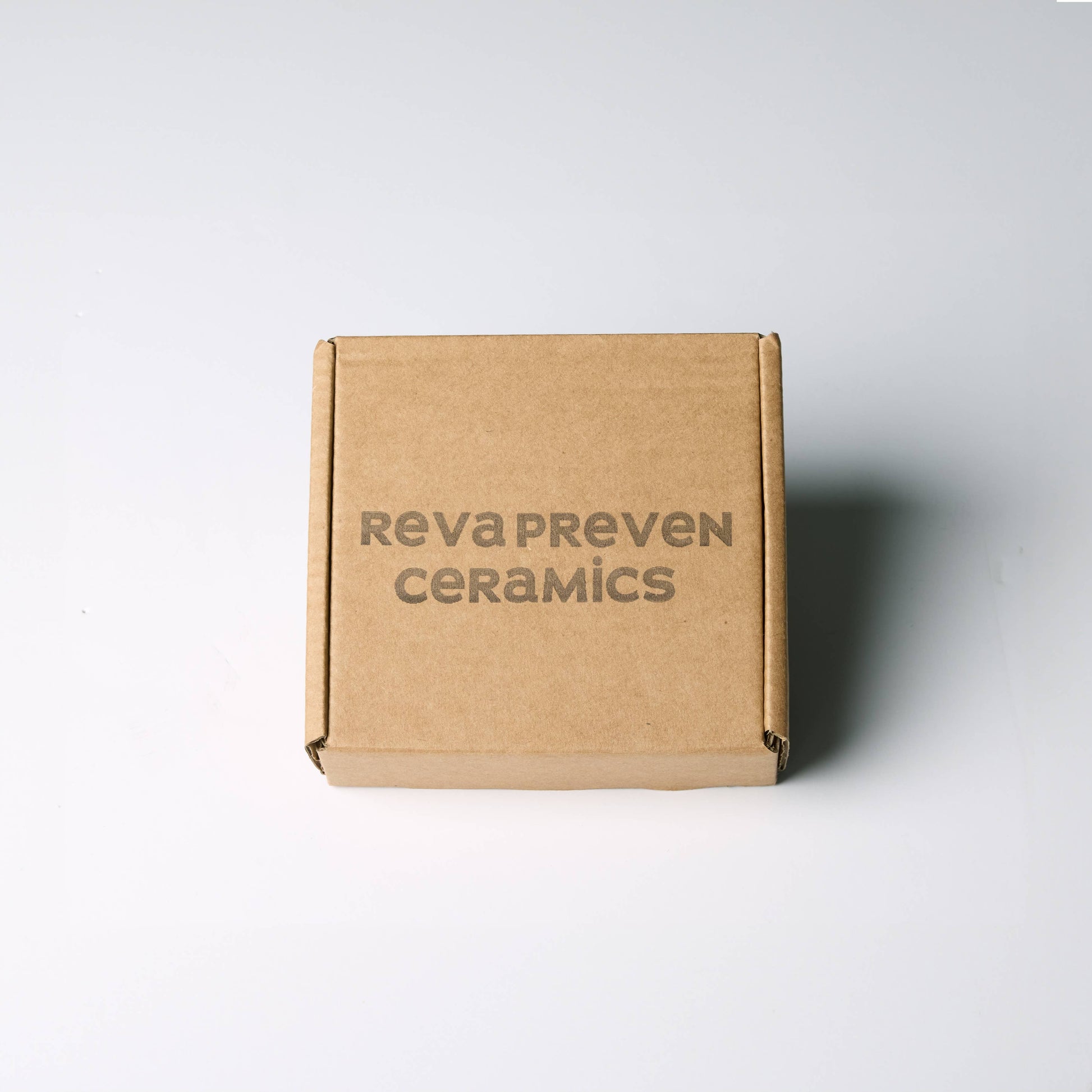 Brown cardboard box with 'RevaPreven Ceramics' branding on a white background