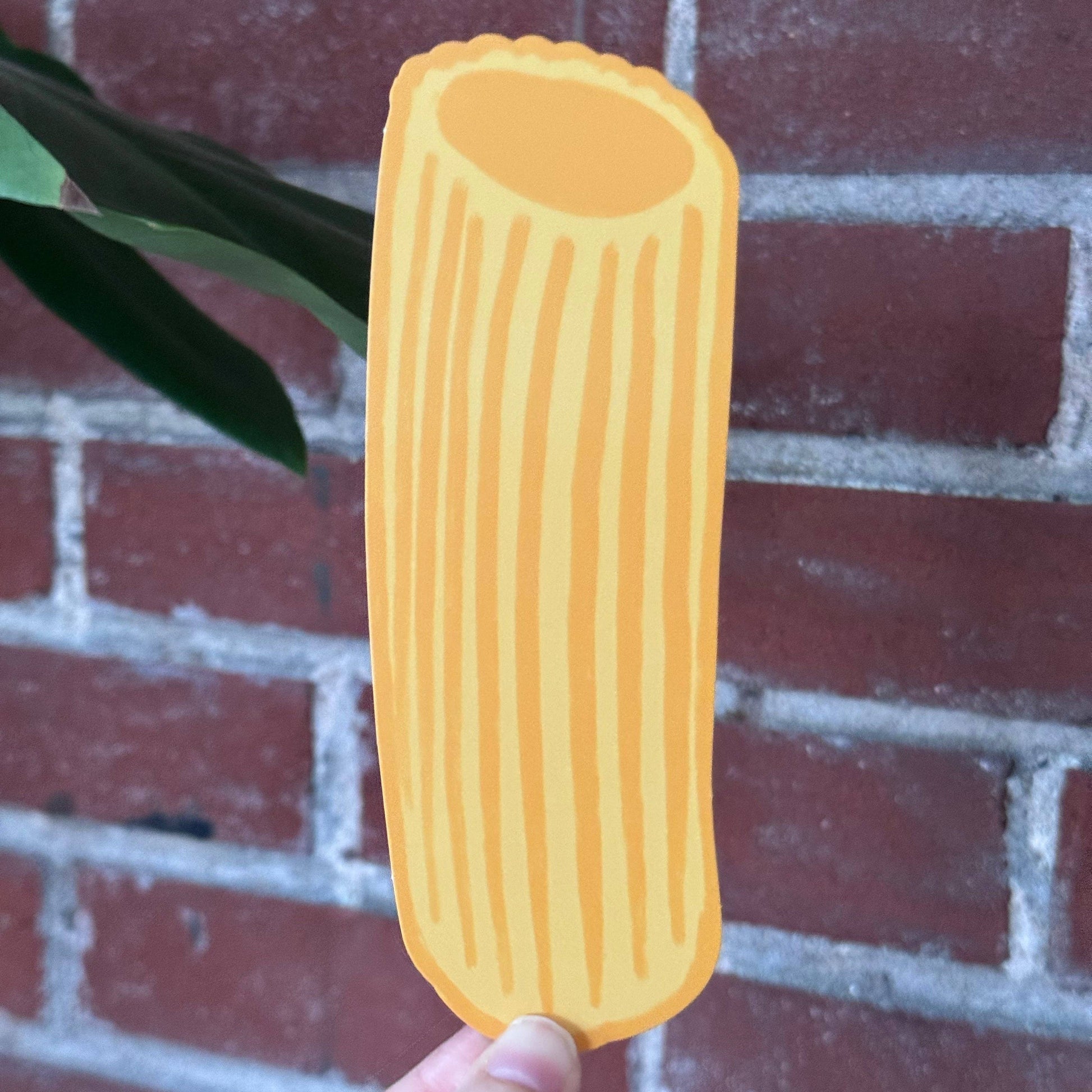 Pasta-shaped bookmark held in front of a brick wall
