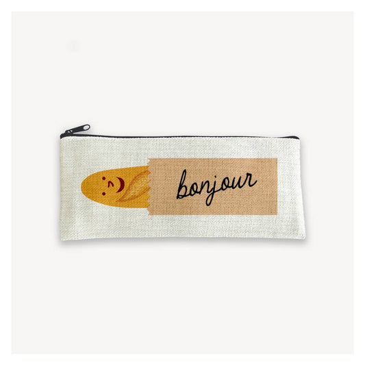 canvas pencil pouch with a smiley faced baguette in a brown paper bag with text on it that reads "bonjour" 